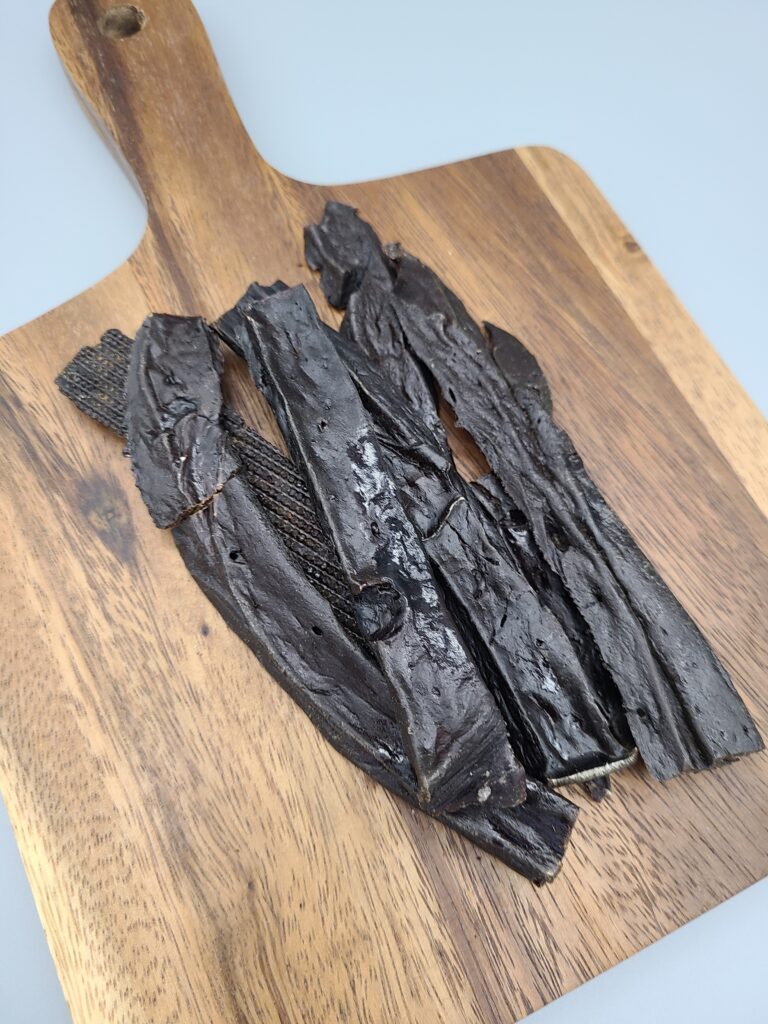 Proper portion sizes of dried beef liver for dogs displayed on a wooden board

